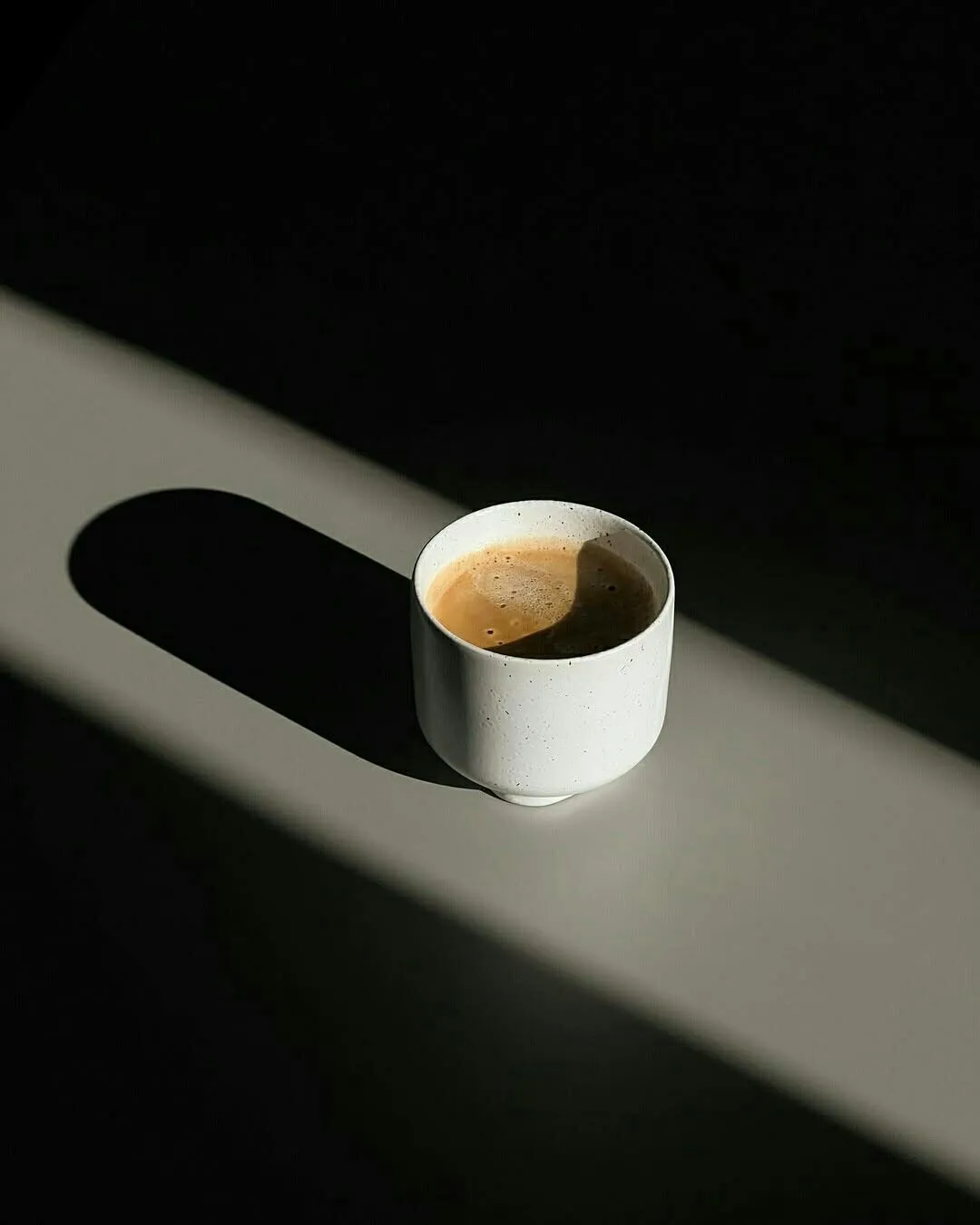 A white coffee cup casting a long shadow